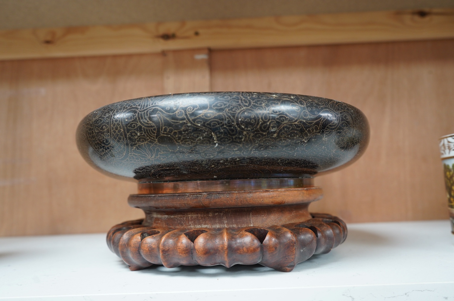 A Chinese black ground cloisonné enamel ‘dragon’ bowl on a carved hardwood stand, 14.5cm high. Condition - fair